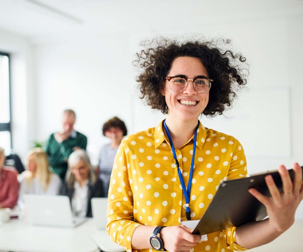 Woman smiling at camera while holding a tablet